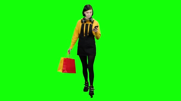 Κορίτσι έρχεται από ένα κατάστημα με πακέτα και ένα τηλέφωνο στα χέρια της. Πράσινη οθόνη — Αρχείο Βίντεο