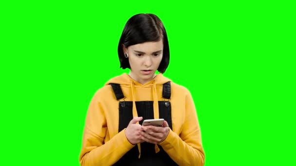 ティーンエイ ジャーは、携帯電話に見えるし、奇妙な写真を見ています。緑色の画面 — ストック動画