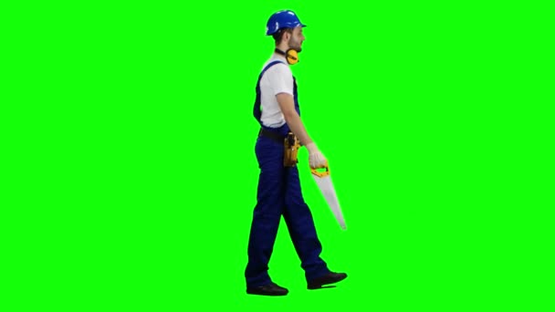 Foreman va en un casco y sierra en su mano. Pantalla verde. Vista lateral — Vídeos de Stock