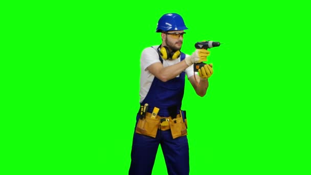 Builder holds a drill in his hands and looks around. Green screen — Stock Video