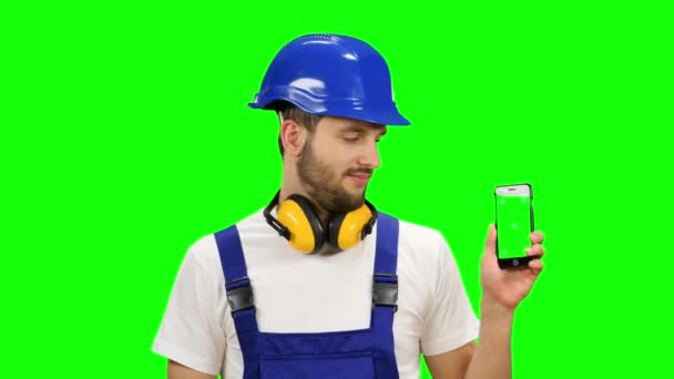 Builder har en telefon i hans händer och visar tummen upp. Grön skärm. Håna upp — Stockvideo