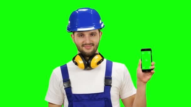 Der Ingenieur hält ein Telefon in der Hand und zeigt den Finger nach unten. Green Screen. Attrappe — Stockvideo