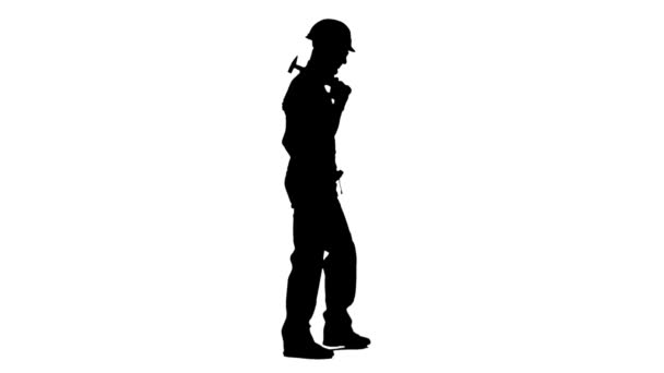 Bauarbeiter mit Hammer in der Hand geht auf die Baustelle. weißer Hintergrund. Silhouette. Seitenansicht — Stockvideo