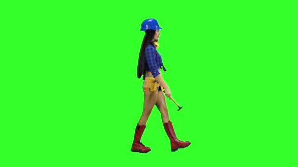 Девушка с длинными волосами несет молоток вид сбоку на зеленом фоне — стоковое видео