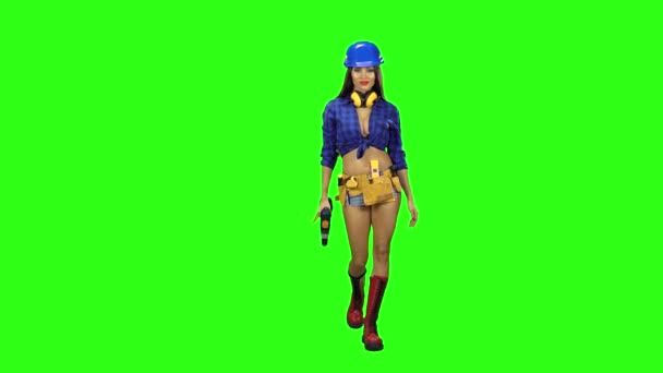 Fille dans les bottes et le casque va avec une perceuse à la main sur fond vert — Video