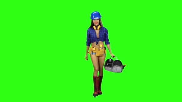 Fille dans les bottes et le casque est livré avec un sac d'outils à la main sur fond vert — Video