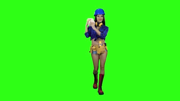 Mädchen in kurzen blauen Helm mit den Brettern auf der Schulter geht auf einem grünen Hintergrund — Stockvideo