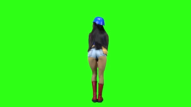 Vista trasera de la chica con casco y pantalones cortos bailando eróticamente sobre fondo verde — Vídeos de Stock