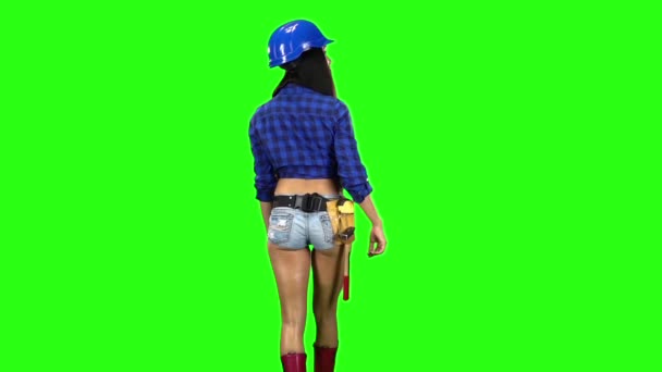 ヘルメットと緑の背景の手ジェスチャーとゆっくり歩いてショート パンツを着ている少女の背面します。スローモーション — ストック動画