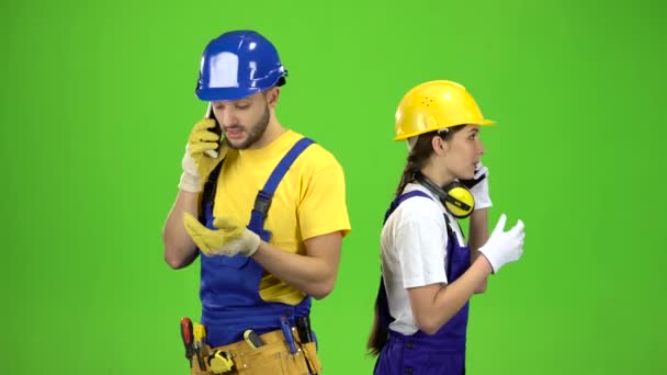 Ingenieurs man met een meisje praten op verschillende telefoons. Groen scherm — Stockvideo
