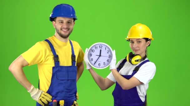Twee bouwers houdt een grote klok en hun duimen opdagen. Groen scherm — Stockvideo