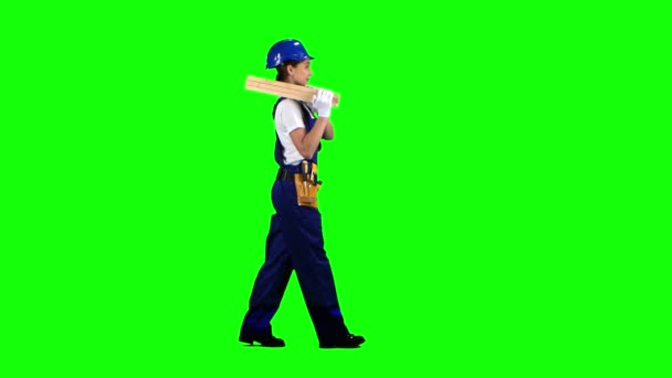 Construction worker wearing a helmet carries three wooden boards. Green screen. Side view — Stock Video