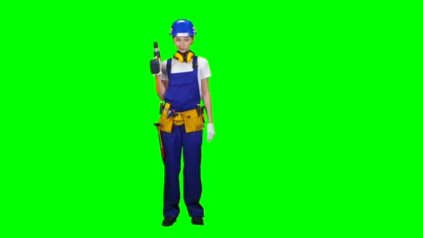 Engineer girl in a helmet and overalls holds a drill in her hands . Green screen — Stock Video