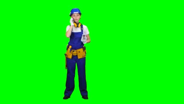 Builder is standing and talking on the phone with a drawing in her hands. Green screen — Stock Video