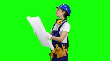 Kız bir kask ve bir çizim onun elinde duruyor. Yeşil ekran