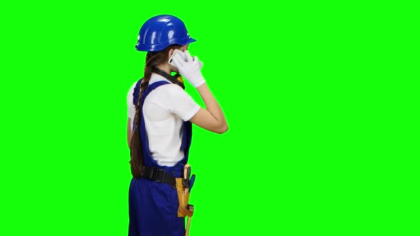 Constructor está de pie con su espalda y hablando por teléfono. Pantalla verde — Vídeos de Stock