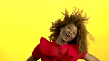 Afro-Amerikan kız atlama ve müzik ile eğleniyor. Sarı arka plan. Ağır çekim