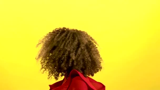 Mulata menina faz moscas cabelo. Fundo amarelo. Movimento lento — Vídeo de Stock