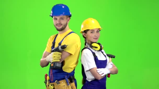 Builder står en kille som innehar en borr, en flicka hammare. Grön skärm. Slow motion — Stockvideo