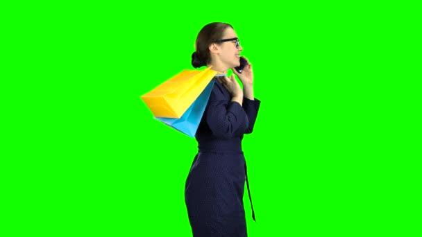 Businesswomen in glasses speaks on the phone and goes to the store, she is in a good mood from shopping. Green screen. — Stock Video