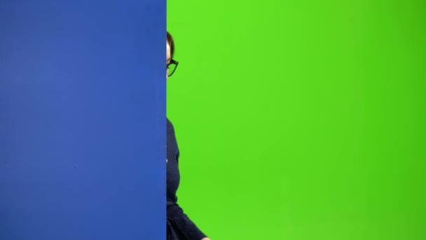 Zakenvrouw kijkt uit achter een blauw bord en toont een thumbs up. Groen scherm — Stockvideo
