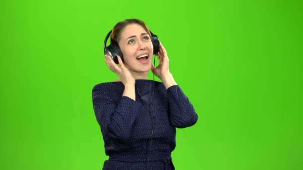 ヘッドホンで音楽を聴いている女の子。緑色の画面 — ストック動画