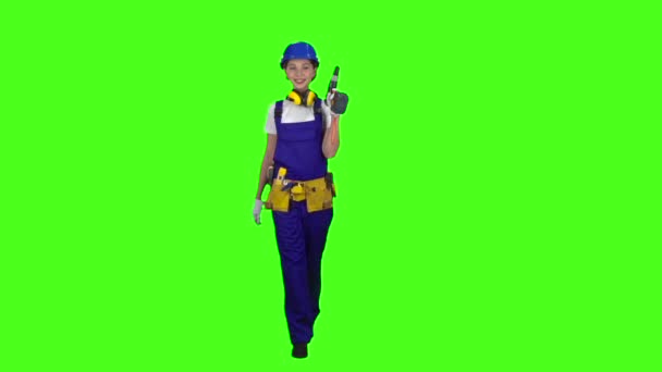 Brigadier meisje komt met een boor in haar handen. Groen scherm. Slow motion — Stockvideo