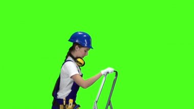 İşçi kız bir matkapla delik duvar merdiveni tırmandı. Yeşil ekran. Ağır çekim