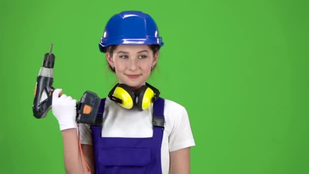 Інженер дівчина в шоломі і комбінезоні тримає в руках дриль. Зелений екран. Повільний рух. крупним планом — стокове відео