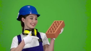Kız Oluşturucu bir tuğla yapımı için taşır ve başparmak gösterir. Yeşil ekran. Ağır çekim. Yakın çekim