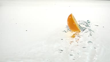 Suya yarım bir orangedrops. Beyaz arka plan. Ağır çekim