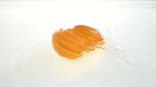 Naranja cae en el agua y escamas a los lóbulos. Fondo blanco. Movimiento lento — Vídeo de stock