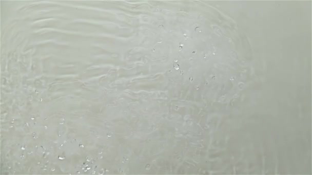 Surface ondulée des éclaboussures d'eau causées par les vibrations sonores. Fond gris. Mouvement lent — Video