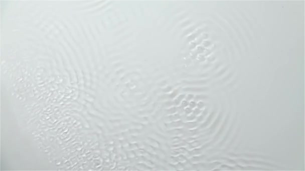 La réflexion de l'eau crée des ondes causées par les vibrations. Fond blanc. Mouvement lent 