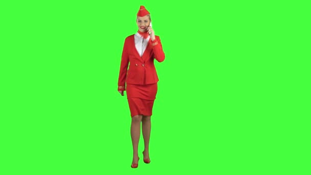 Stewardess speaks on the phone and paces into the distance. Green screen. — Stock Video