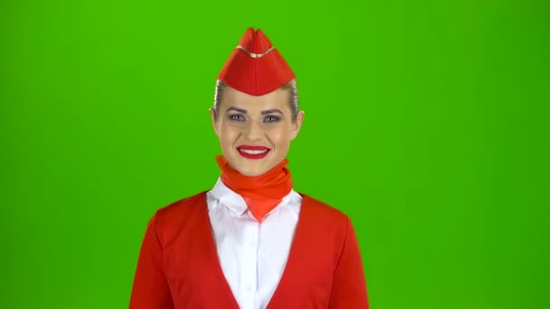 Stewardess in a red suit winks a slight flirt sends an air kiss. Green screen — Stock Video