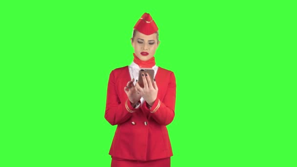 Αεροσυνοδός με την κόκκινη ενδυμασία φαίνεται στο τηλέφωνο και είναι έκπληξη. Πράσινη οθόνη — Αρχείο Βίντεο