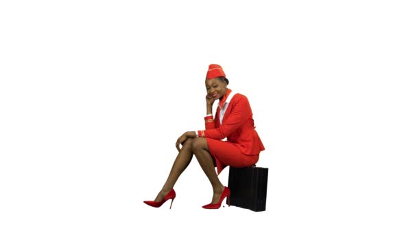 African American stewardesa w czerwonym kolorze siedzi na uśmiech walizkę. Kanał alfa — Wideo stockowe