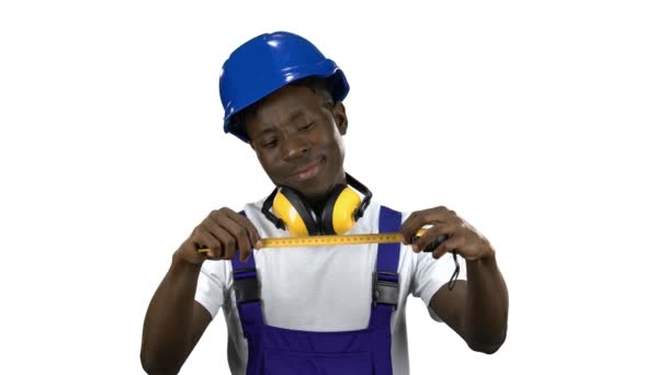 Constructor afroamericano toma medidas con una cinta métrica amarilla. Canal alfa — Vídeos de Stock