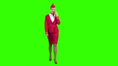 Kırmızı elbiseli bir hostes üstünde belgili tanımlık telefon ve adım ötede konuşuyor. Yeşil ekran. Ağır çekim