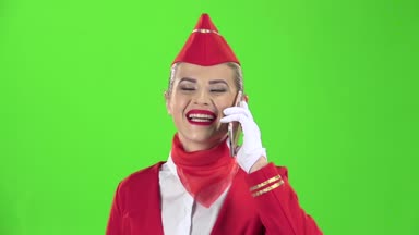 Kırmızı elbiseli bir hostes telefonda konuşuyor. Yeşil ekran. Ağır çekim
