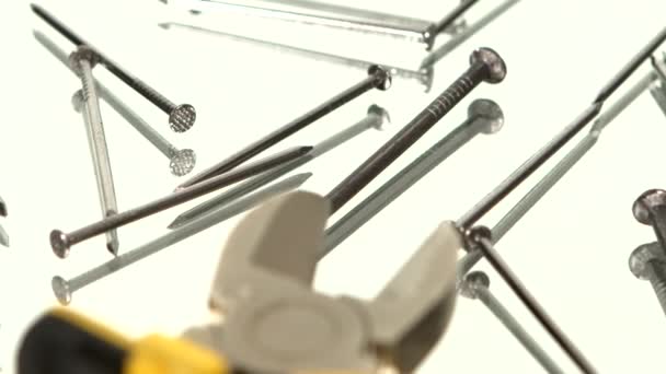 Mini-Cutter mit gelbem, grauem Griff auf weißem zwischen vielen Nägeln, Drehung, Spiegelung, Nahaufnahme — Stockvideo
