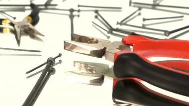 Gri ve kırmızı pense ve gri, sarı yuvarlak burun pensesi beyaz, çivilerin arasında, yansıma, dönüş, kapat