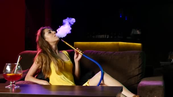 Chica fumando shisha acostado en el sofá en la cafetería. Movimiento lento — Vídeos de Stock