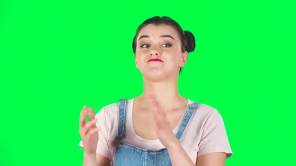 Girl with two hair-buns claps her hands indifferently on green screen. Slow motion — 图库视频影像