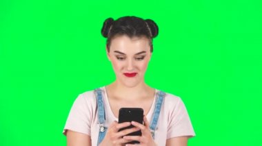 Genç gülümseyen kadın telefonuyla yeşil ekranda mesaj atıyor, ağır çekimde.