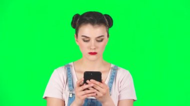 Kız sinirli bir şekilde telefonuyla yeşil ekranda mesaj atıyor, ağır çekimde.
