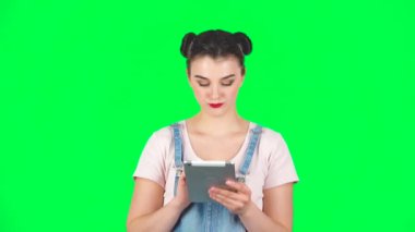 Genç gülümseyen kadın tablet bilgisayarında yeşil ekranda mesaj atıyor, ağır çekimde.