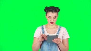 Üzgün kadın stüdyodaki tablet bilgisayarından yavaş çekimde bilgi okuyor.
