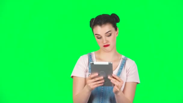 Улыбающаяся женщина читает информацию на планшетном компьютере в студии, замедленная съемка — стоковое видео